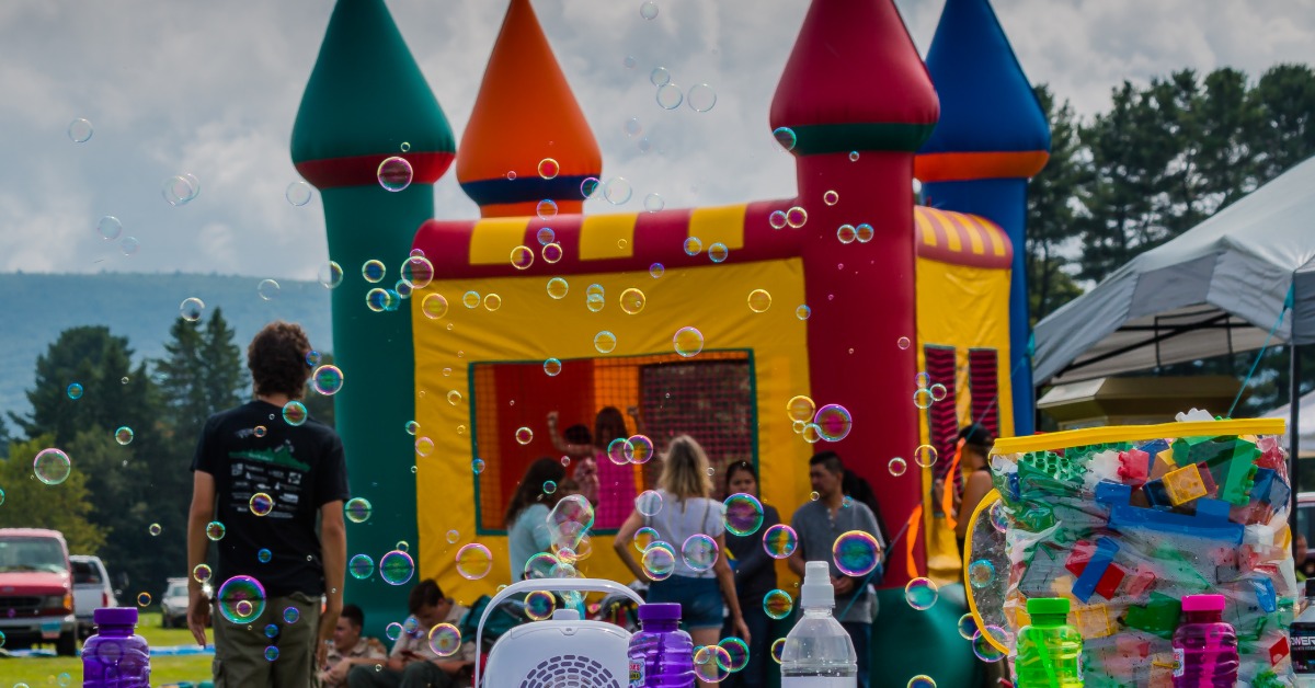 An inflatable bounce castle outside during the daytime. A crowd of parents and children surround the inflatable.