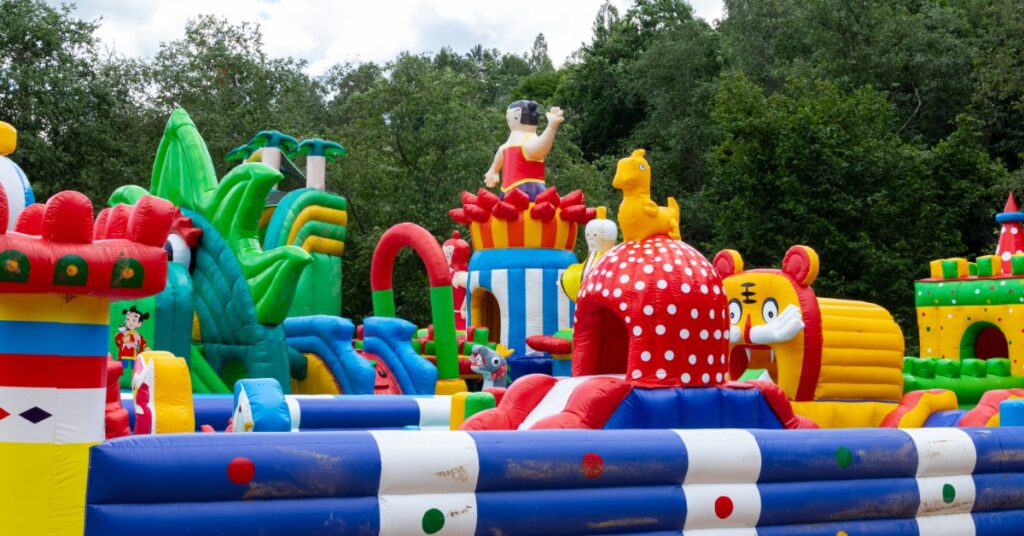  A massive inflatable obstacle course installed outside in front of many green trees during the daytime.